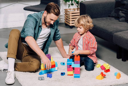 男人和小儿子在家玩彩色塑料积木