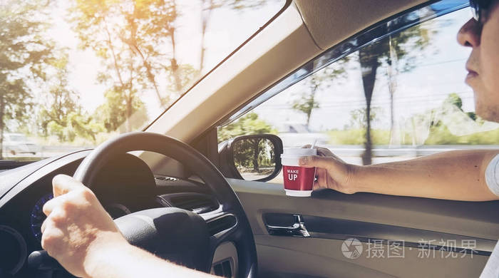 一个人开车,一只手拿着咖啡杯,另一只手