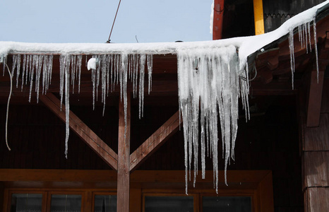 许多长长的冰柱挂在小屋的屋顶上