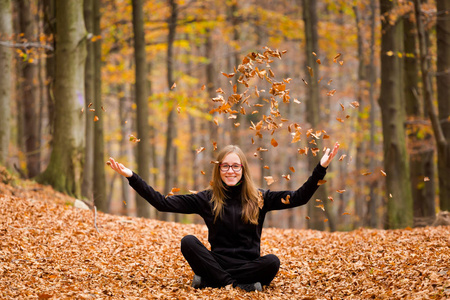 秋天的风景与年轻的白种人女孩玩树叶在波兰的贝斯基迪山，在五彩缤纷的秋天抓斗。