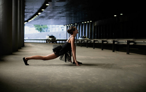 年轻漂亮的女孩芭蕾舞演员在隧道里做体操姿势。 灵活性和敏捷性。