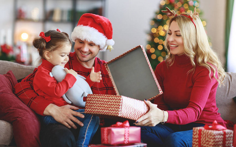 幸福的家庭父母和孩子的女儿在圣诞节早上打开礼物