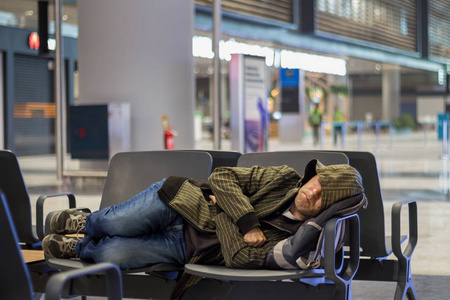年轻人在机场候机楼等飞机时睡觉