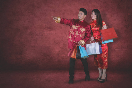中国新年概念。 年轻的亚裔男子在和妻子买礼物后指着工作室里的东西