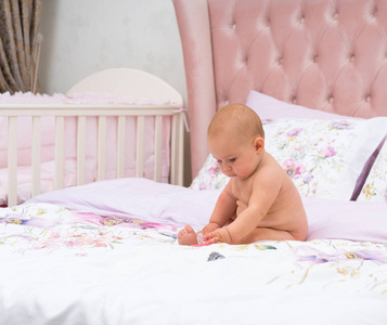 可爱的小女孩独自在托儿所的床上玩耍，有时尚的粉红色装饰和复制空间