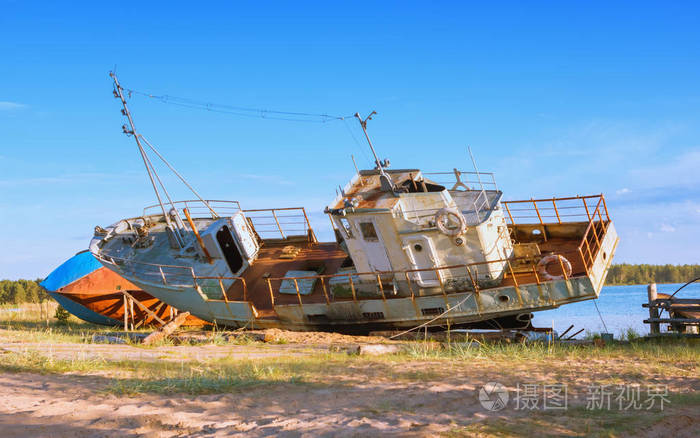 一个阳光明媚的夏天古老的废弃生锈的渔船站在沙质河