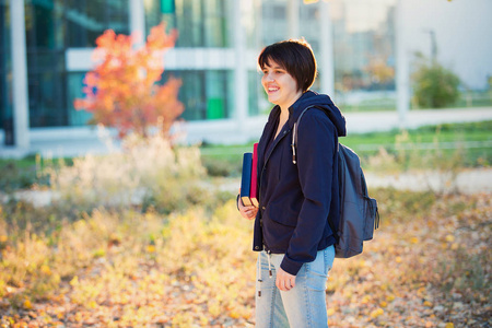 学生女孩去大学户外肖像，拿着书和背包。