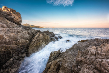 波在洛扎里的科西嘉的岩石海岸上洗涤，黎明在远处的卢梭破晓