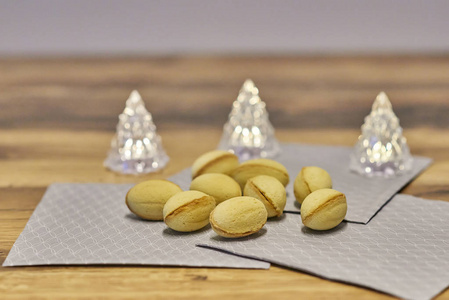 灰餐巾纸上满是核桃形状的黄油饼干，背景中有三盏圣诞树灯