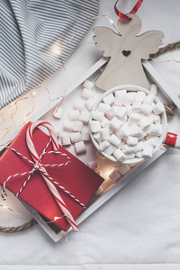 新年或圣诞节平躺顶景与热可可咖啡巧克力与棉花糖杯圣诞节庆祝红色礼物盒在木制托盘在床上与灯。 概念博客社交媒体2019