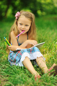 公园里有铅笔和便条的可爱小女孩