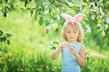 可爱的有趣女孩，在花园里有复活节彩蛋和兔子耳朵。 复活节的概念。 复活节猎蛋的笑孩子。 有蛋春概念的孩子在公园里