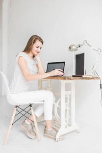 年轻的女商人在家工作, 在平板电脑上画画。创意斯堪的纳维亚风格的工作空间