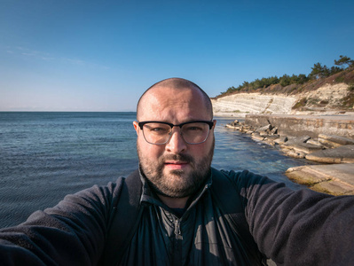 戴眼镜的人在海边自拍和岩石背景, 旅行概念