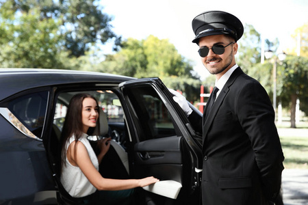 英俊的司机为年轻的女商人打开车门。 司机服务