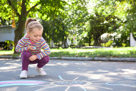 小孩子用彩色粉笔在沥青上画画。 文本空间