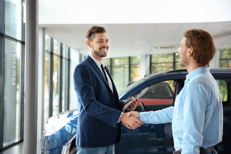 顾客和推销员与汽车经销商握手