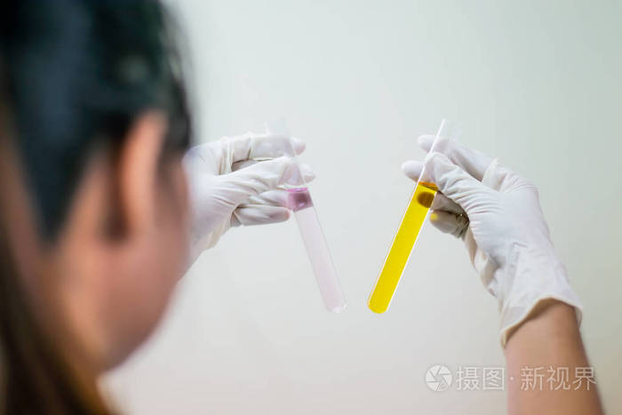 试管中的彩色液体,左手拿着科学家手套,隔离在浅色的平壁上