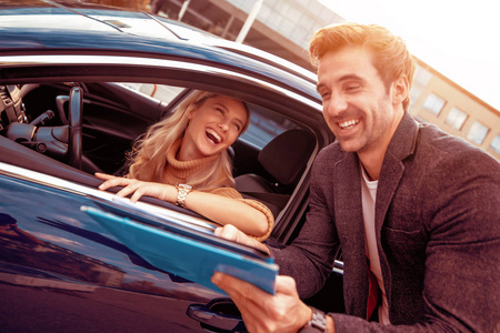 在汽车沙龙和汽车经销商在一起的快乐女人。