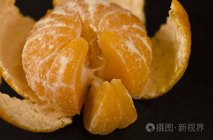 多汁的橘色橘子皮和切片放在黑色的桌子上