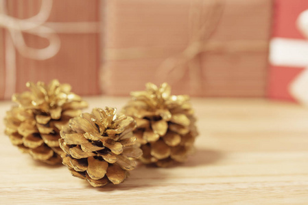 金色松果闪闪发光的圣诞节和礼品盒装饰在木桌的背景。 复制空间。