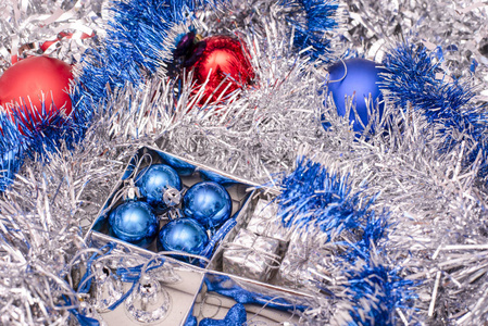 圣诞节玩具包括蓝色的星星, 蓝色的圣诞球, 银色的铃铛和礼品盒在盒子之间的银