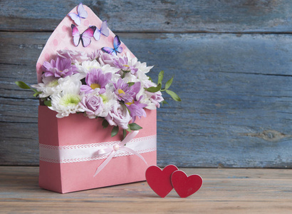 美丽的花束，木桌背景上有两颗红色的心。情人节背景