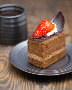 巧克力蛋糕切片，放在咖啡杯旁边的碎木片上