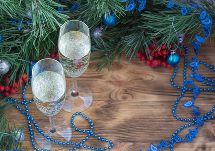 圣诞节和新年仍然生活组成与两个香槟杯松树，尖顶红罗万浆果，蓝色和银球花环装饰复制空间