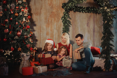 圣诞家庭打开礼物袋期待神奇的灯光在夜晚圣诞树阁楼内部