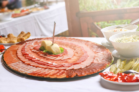 美味的猪肉干肉片在大盘子上装饰成圆圈。 婚礼上有肉片的大盘子。