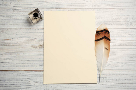 羽毛笔墨水井和空白羊皮纸上的木制桌子顶部视图。 文本空间