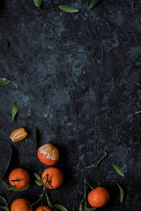 新鲜的柑橘与叶子在纹理黑暗的背景与复制空间。顶视图