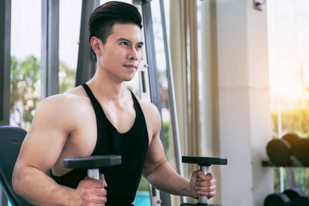 肌肉男健美运动员在健身健身房训练哑铃。 健康的生活方式和健美的概念。