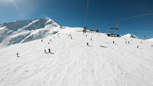 滑雪缆车，座位经过山上，可以看到人们在斜坡上滑雪和滑雪板