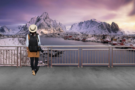 亚洲女游客穿着休闲风格，简单的背包和相机看着挪威的冬天。