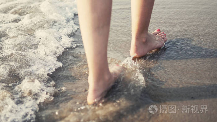 在赤脚的女性脚下行走,溅在海水上,电影中的稳定镜头