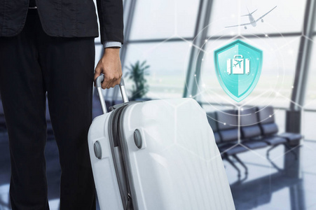 旅游保险盾牌保护旅行在虚拟屏幕上对商人和手提箱在机场的背景下保险在线保险数字技术的概念。