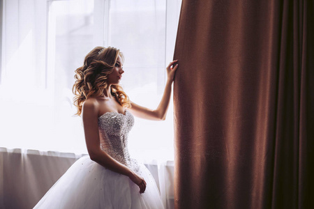新娘穿着豪华的白色连衣裙关上窗户
