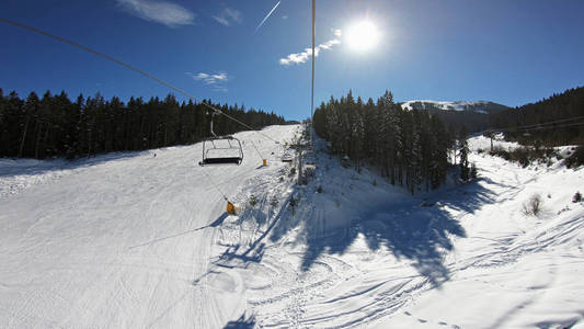 滑雪电梯，座位经过山上，可以看到人们在斜坡上滑雪和滑雪板