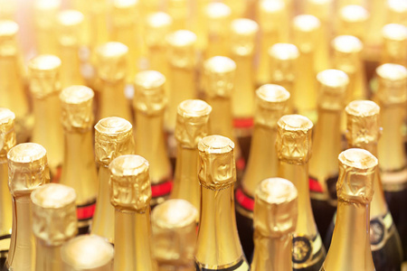 许多瓶香槟与金箔顶部成排。 派对庆祝背景。 婚礼和圣诞饮料。
