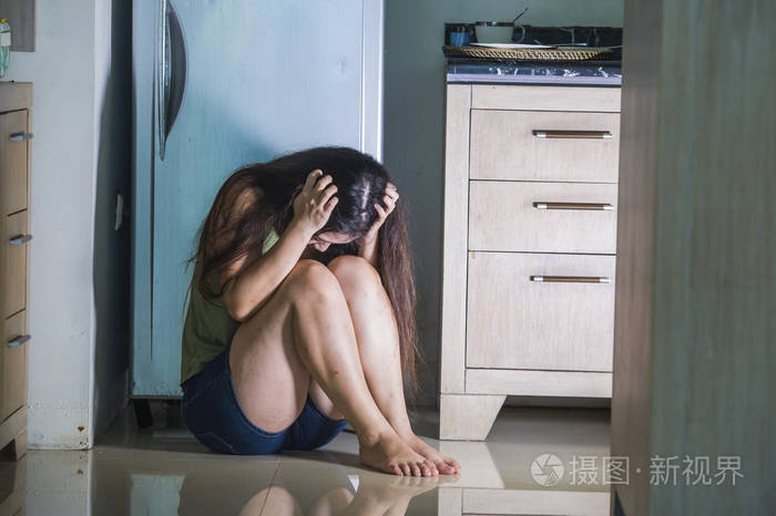 年轻的绝望和沮丧的女人在家厨房地板上哭泣,害怕家庭暴力和性虐待的