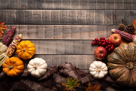 秋天枫叶的顶部视图，南瓜和红色浆果在旧的木制背景。 感恩节的概念。