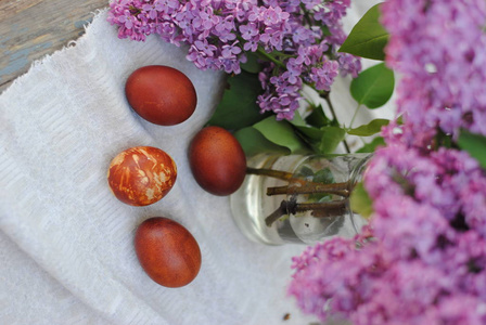 紫丁香枝条背景上复活节彩蛋的照片。