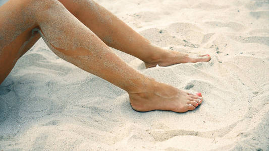 s legs on the beach. woman enjoys summer vacation and plays with