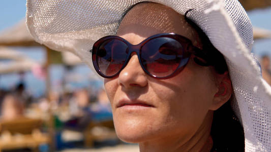 特写年轻的夏天女人戴着帽子和太阳镜的脸。 户外生活方式