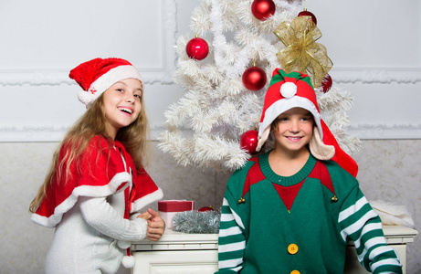 家庭度假传统。孩子们欢庆圣诞节。兄弟姐妹们准备庆祝圣诞节或迎接新年。孩子们穿着圣诞老人和精灵的服装。冬季化装舞会的概念。圣诞快乐