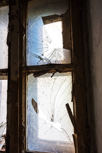 一座废弃的神秘房子窗户上的破碎玻璃。 破窗玻璃的恐怖照片。 阴郁的室内抑郁背景设计悲剧恐怖万圣节