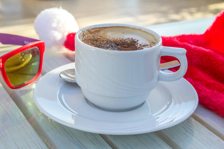 杯咖啡和圣诞老人帽子和红色眼镜在木桌上, 圣诞节庆祝