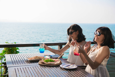 休闲概念。 美丽的女孩正在海边餐馆吃饭。 美丽的女孩正在享受桌子上的食物。